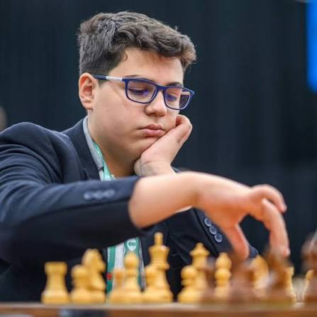 GM Yağız Kaan Erdoğmuş at the board, reaching for a piece